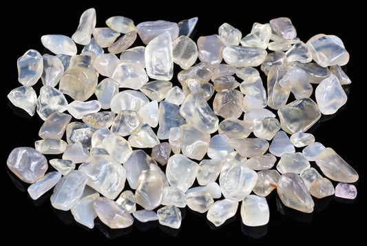 A pile of small, smooth, translucent white and pale stones on a dark surface.