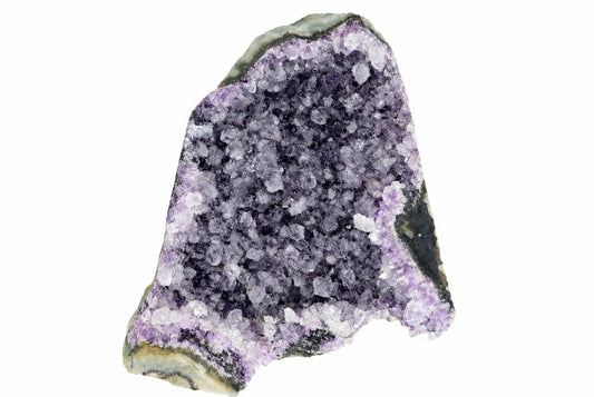 A rough amethyst geode slice with purple and clear crystals on a dark, greenish-grey rock matrix against a white background.