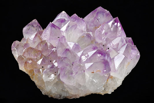 A cluster of purple and clear amethyst crystals on a rough base, set against a black background.