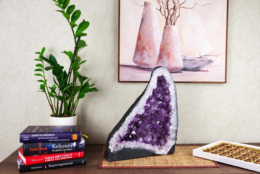 A large amethyst geode slice with purple crystals and white lining sits on a dark surface.