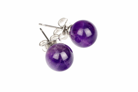 A pair of round purple amethyst stud earrings with silver-toned posts and butterfly backs on a white surface.