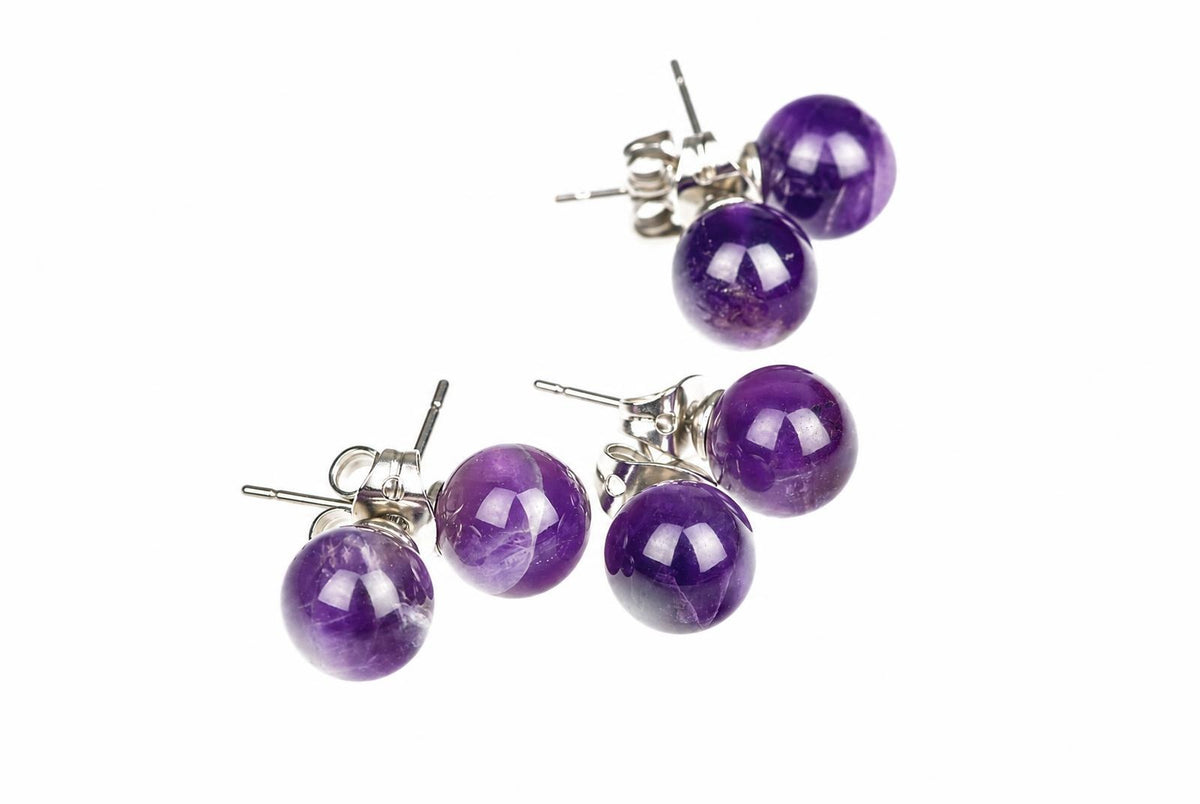 Round purple stud earrings with pale internal streaks, shiny posts and butterfly backs are arranged on a white background.