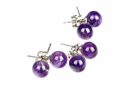 Round purple stud earrings with pale internal streaks, shiny posts and butterfly backs are arranged on a white background.