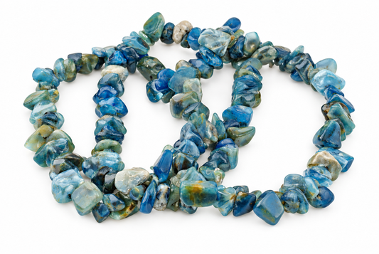 A bracelet made of irregular blue, green and white apatite chips arranged in a loose coil on a white surface.