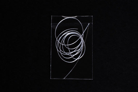 A clear plastic bag containing a coil of white string against a black background.