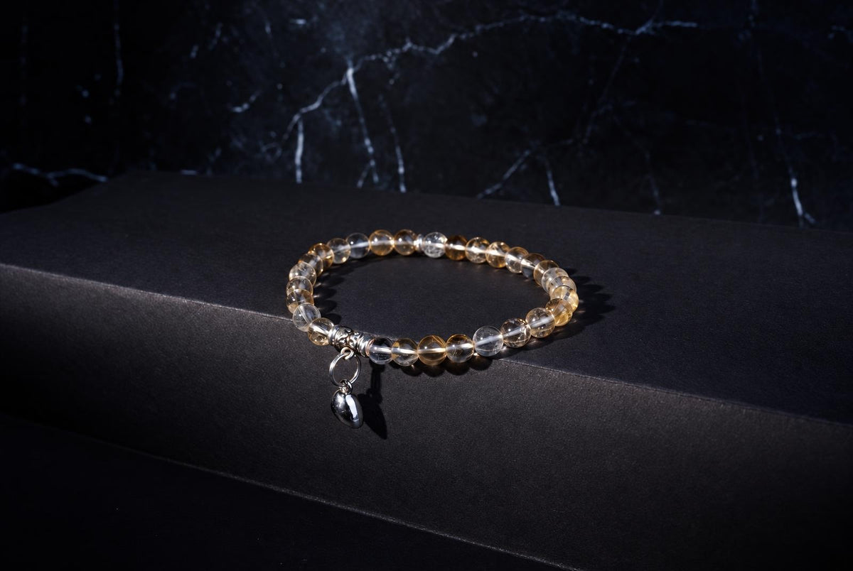 A bracelet with clear and yellow beads, a silver charm, on a dark surface.