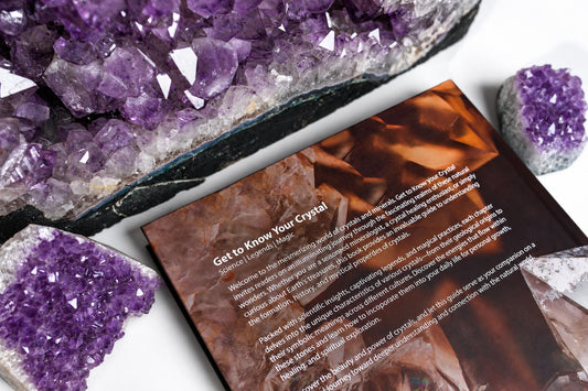 The back cover of Get to Know Your Crystal lies on a white surface among purple crystal clusters.