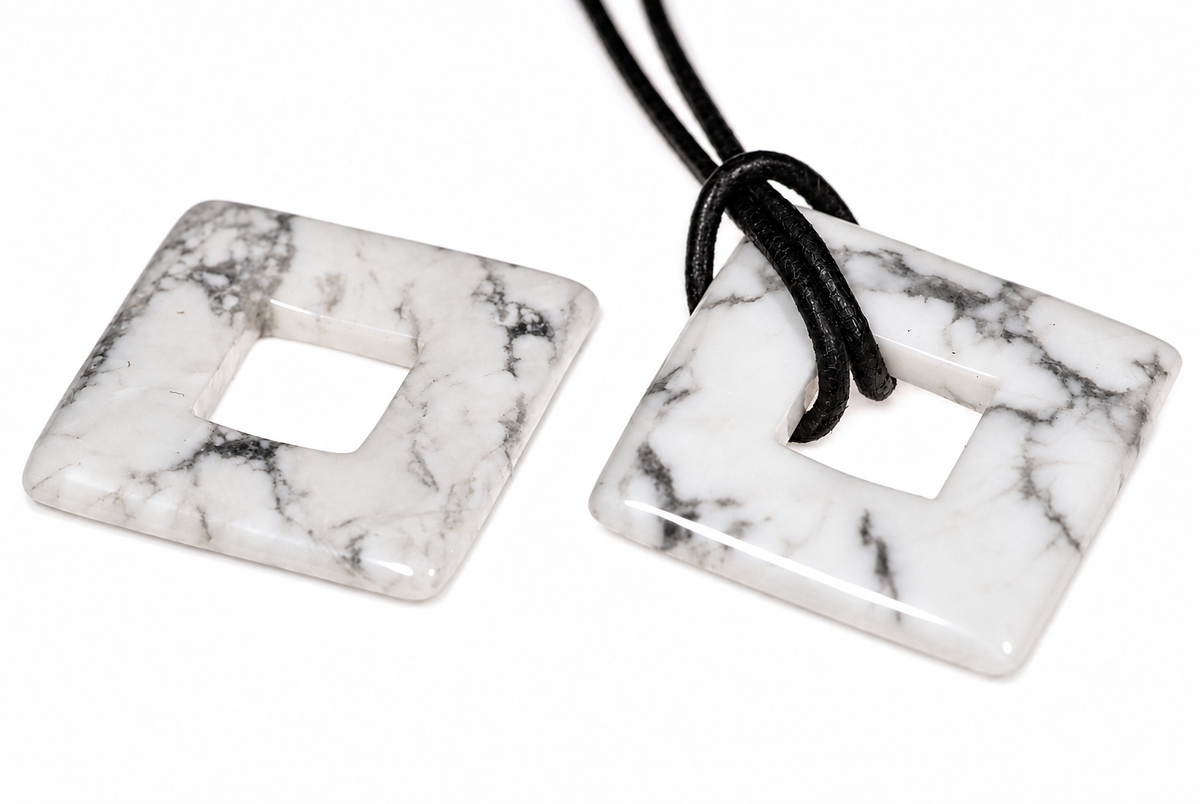 Two square, white and grey veined stone pendants with a central hole; one has a black cord threaded through it.
