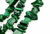 A strand of polished green malachite chips with natural banding, arranged on a white surface.