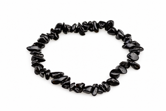 A bracelet made of irregular black chips, possibly obsidian, arranged in a circle on a white surface.