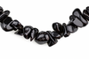 A necklace of glossy black obsidian chips arranged in a curved line on a white background.