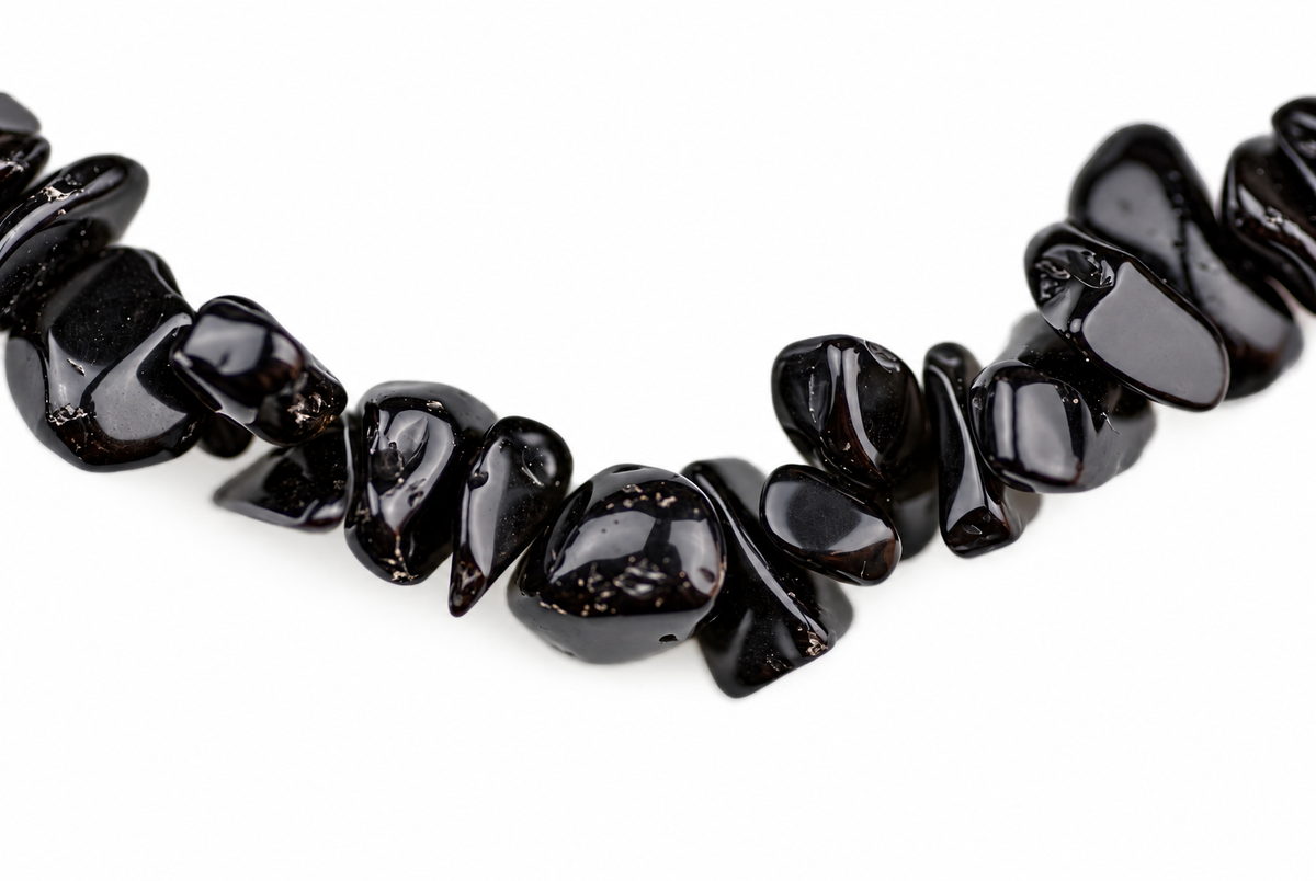 A necklace of glossy black obsidian chips arranged in a curved line on a white background.