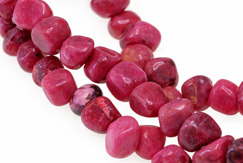 A strand of polished, irregular pink and dark red rhodonite chips arranged on a white surface.