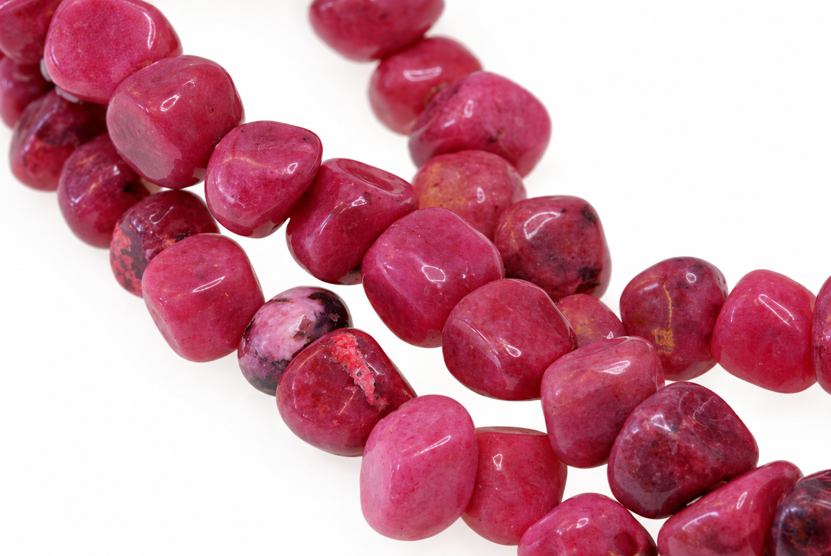 A strand of polished, irregular pink and dark red rhodonite chips arranged on a white surface.