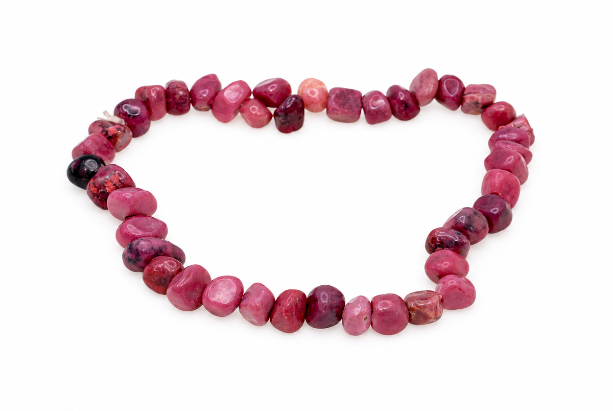 A bracelet of polished rhodonite chips in shades of pink, red and black on a white surface.
