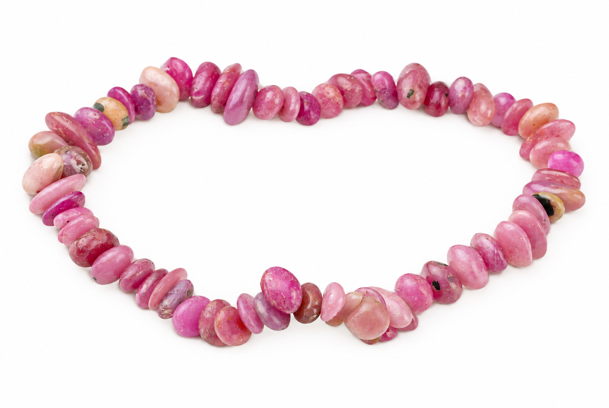 A bracelet made of polished, oval beads in various shades of pink and red, arranged on a white surface.