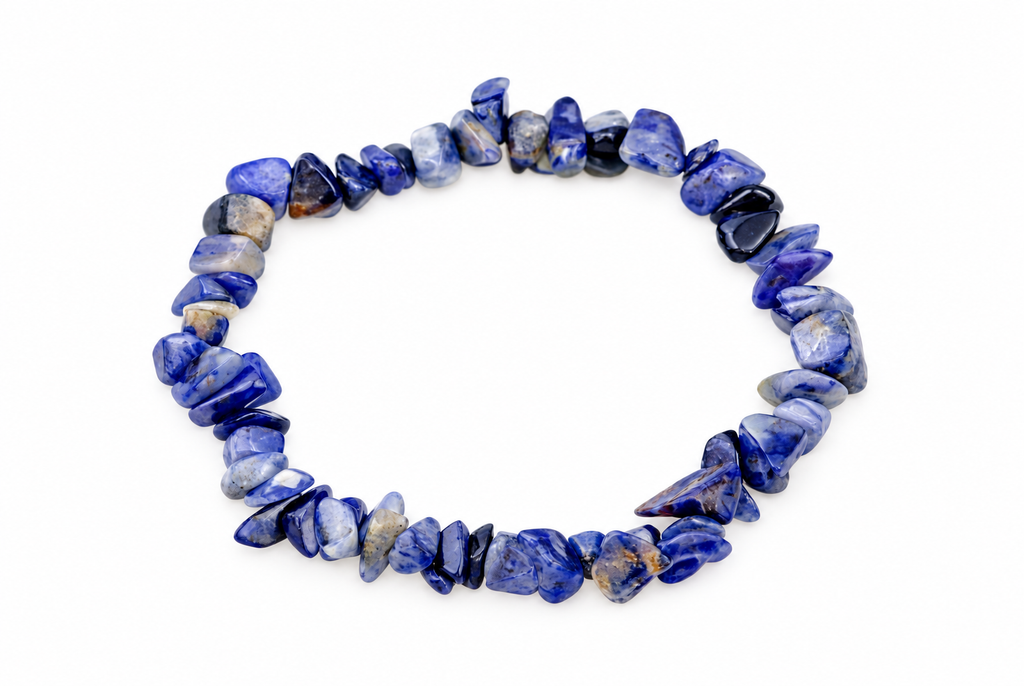 A bracelet made of polished sodalite chips in shades of blue, white and black arranged on a pale surface.