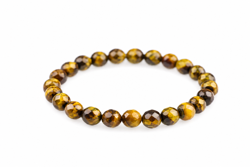 A bracelet of faceted round beads in yellow, brown and black tones arranged on a white surface.