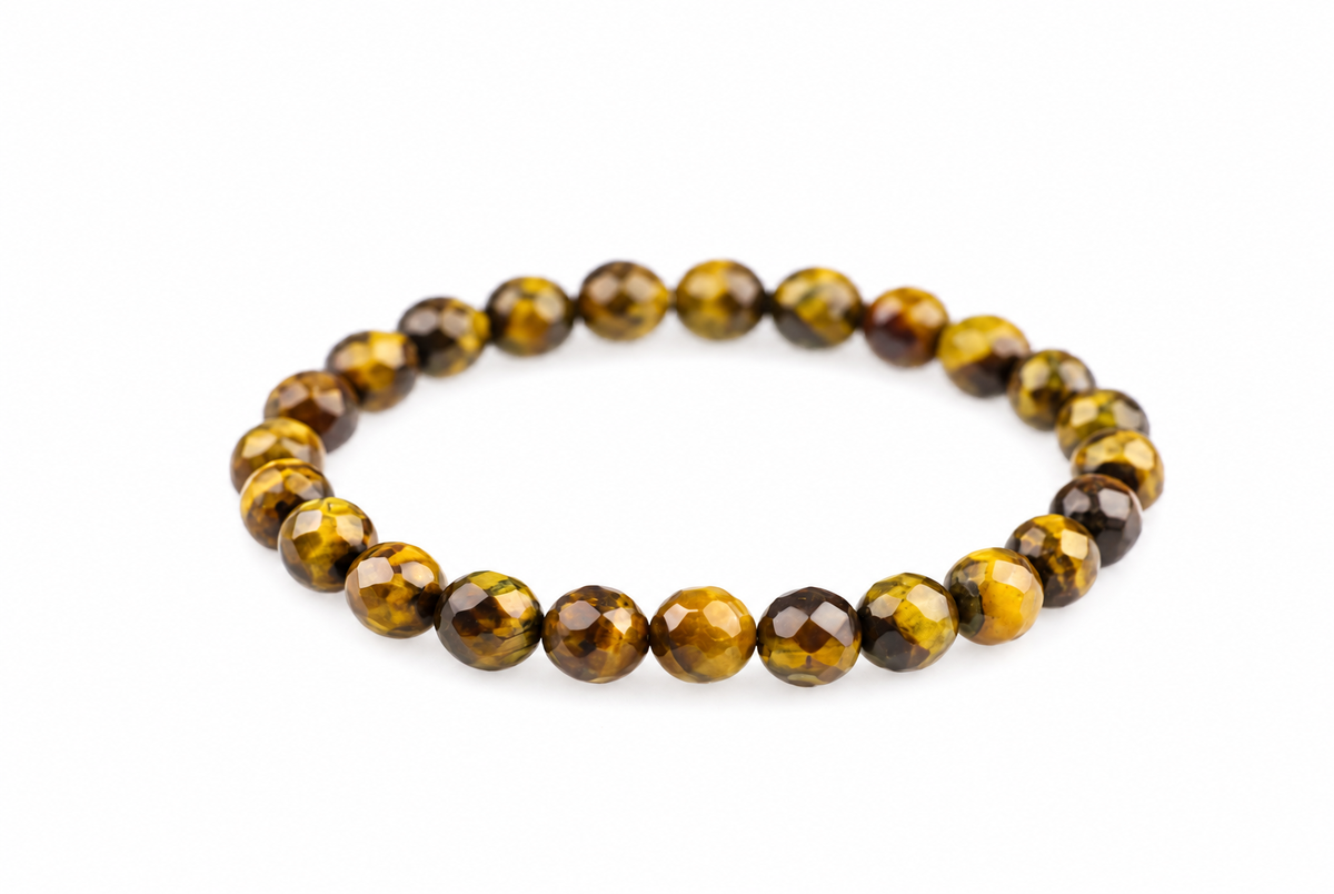 A bracelet of faceted round beads in yellow, brown and black tones arranged on a white surface.