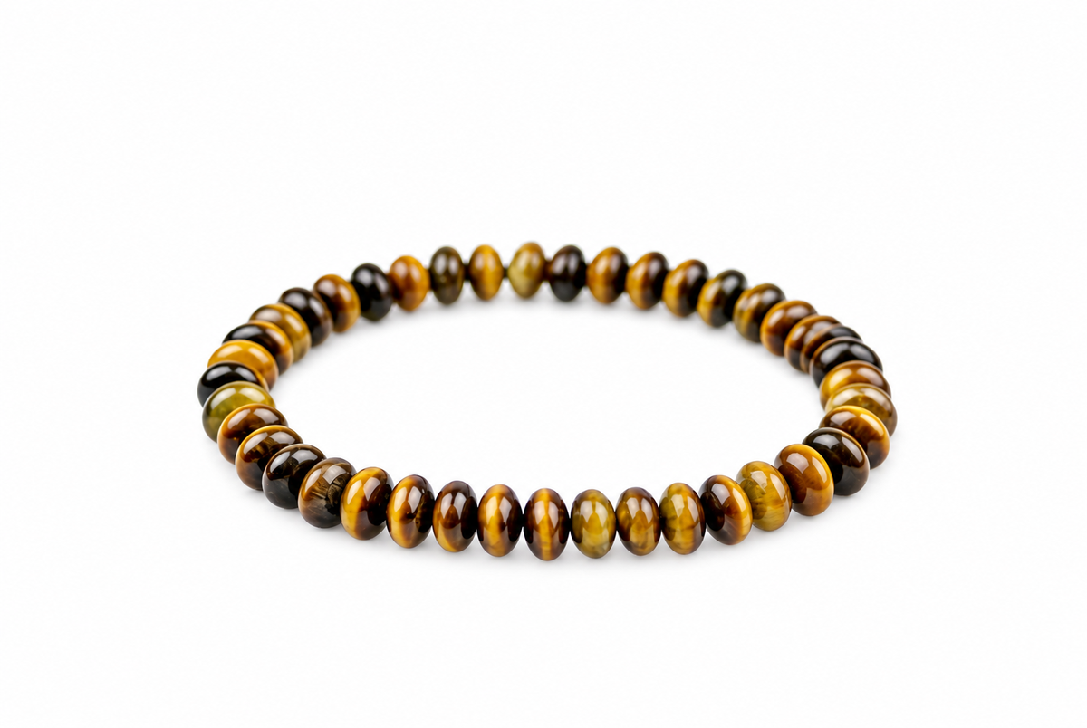 A bracelet of flattened round golden-brown and dark beads forms an oval on a white surface.
