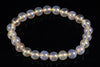 A bracelet of round, pale yellow and white agate beads with a milky sheen on a dark surface.