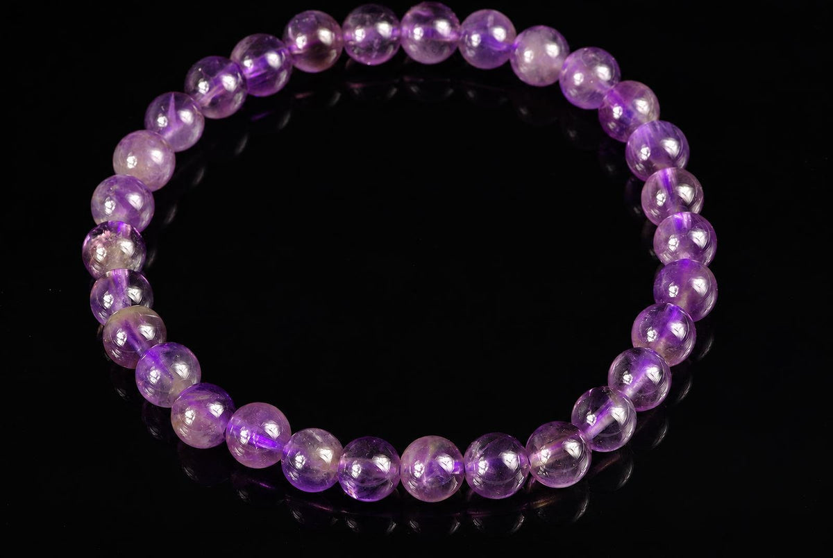 A bracelet of round, translucent purple beads arranged in a circle on a dark surface.