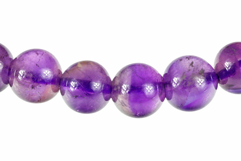 A row of round, polished purple amethyst beads on a white background.