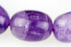 Three round purple beads with visible surface texture and light reflections on a pale background.