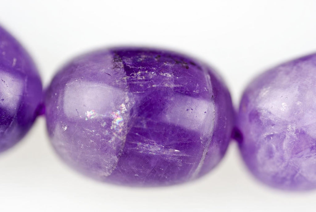 Three round purple beads with visible surface texture and light reflections on a pale background.