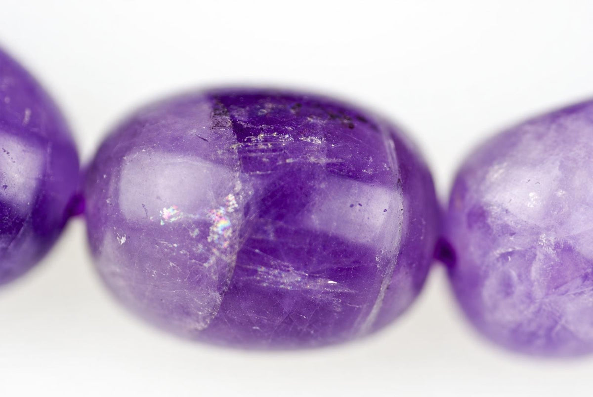 Three round purple beads with visible surface texture and light reflections on a pale background.