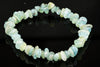 A bracelet made of irregular, polished chips in pale blue, green and white tones on a dark reflective surface.