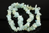 A bracelet made of irregular chips in pale blue, green and white tones on a dark reflective surface.