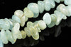 A strand of polished aquamarine chips in pale blue and green tones, arranged on a dark reflective surface.