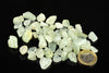 A pile of pale green and white rough stones on a dark surface, with a one euro coin for scale.