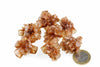 A cluster of brownish, translucent aragonite crystals with a hexagonal shape sits on a white surface next to a one-euro coin.