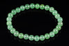 A bracelet of round, light green aventurine beads arranged in a circle on a dark surface.
