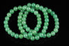 A green Aventurine bracelet with round beads arranged in loops on a dark surface.