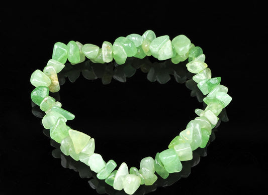 A bracelet made of irregular green aventurine chips arranged in a circle on a dark reflective surface.