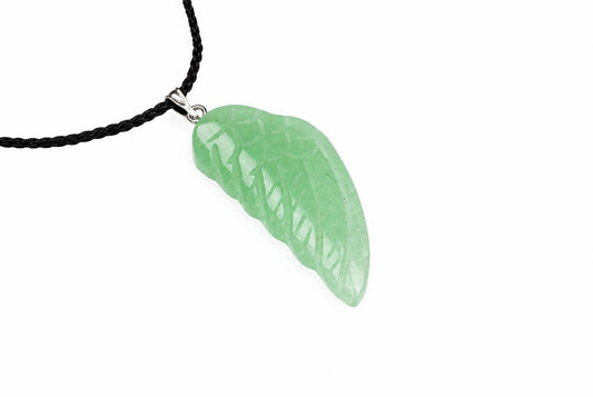 A light green leaf-shaped pendant with carved veins hangs from a black cord on a white surface.