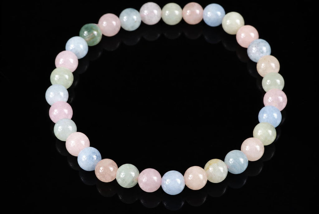 A bracelet of round beads in pastel pink, blue, green and cream colours on a dark surface.