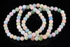 A beryl bracelet with round beads in pastel pink, blue, green and peach on a dark reflective surface.