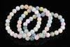 A beryl bracelet with round beads in pastel pink, blue, green and yellow on a dark reflective surface.