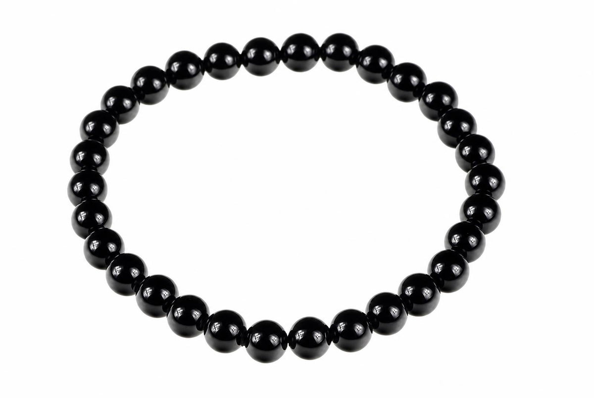 A bracelet made of round black beads arranged in a circle on a white background.