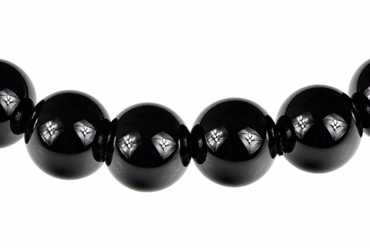 A row of glossy black spherical beads with silver-toned floral inlays, set against a plain white background.
