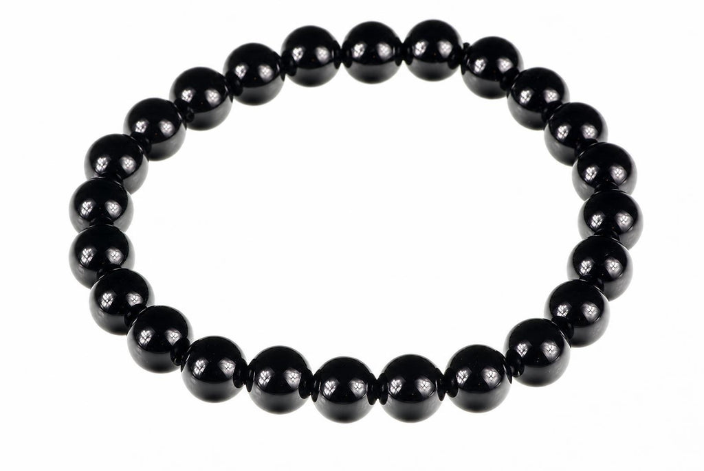 A bracelet made of round, glossy black beads arranged in a circle on a white background.