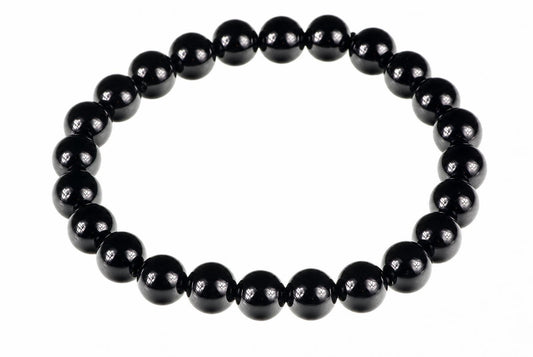 A bracelet made of round, glossy black beads arranged in a circle on a white background.