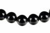 A row of large, round black beads with small dark spacers on a white background.