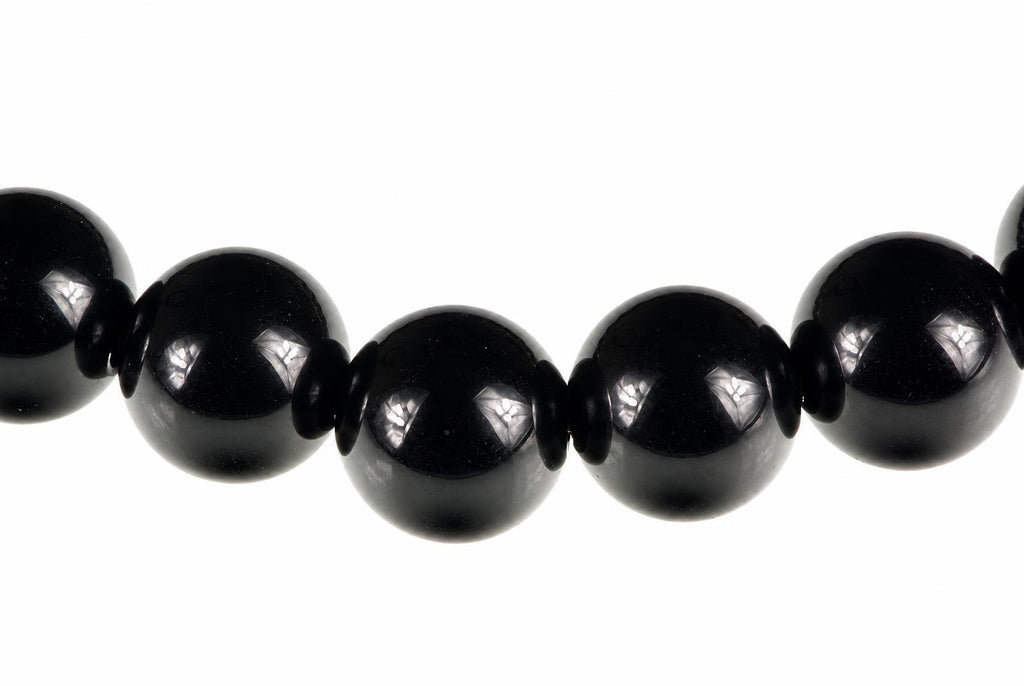A row of large, round black beads with small dark spacers on a white background.