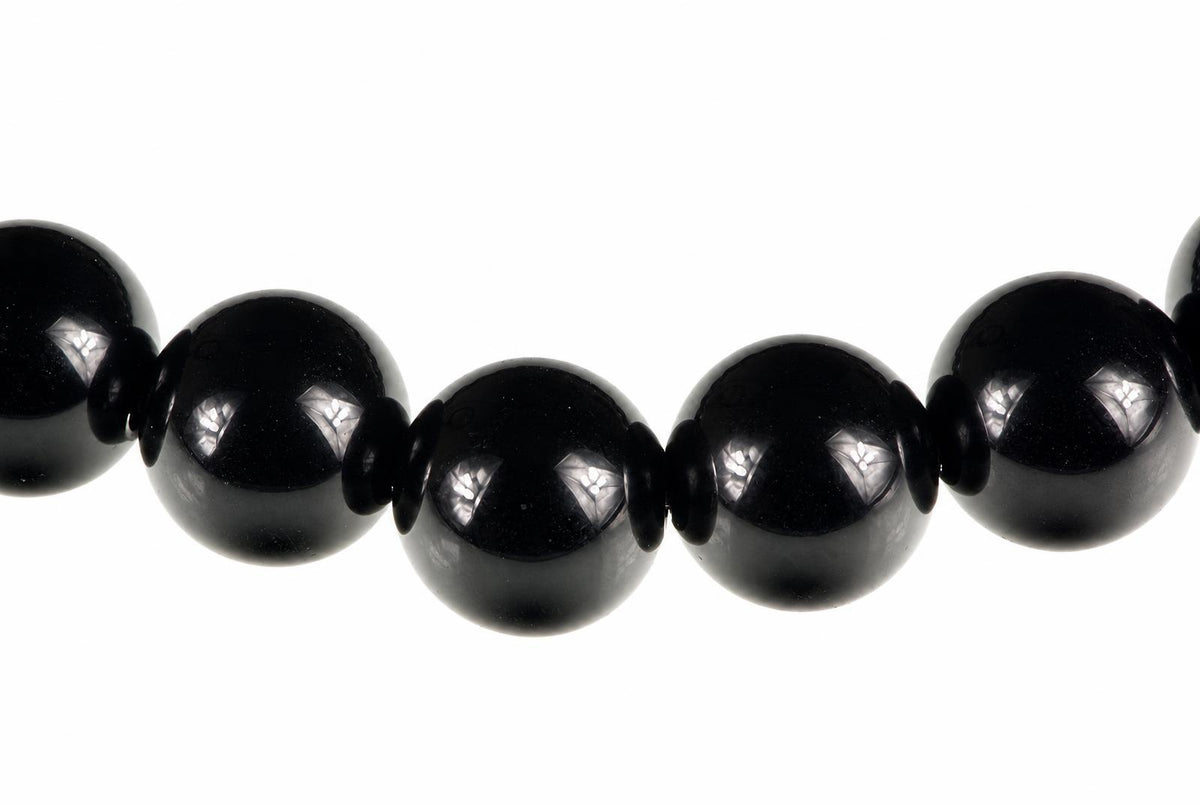 A row of large, round black beads with small dark spacers on a white background.