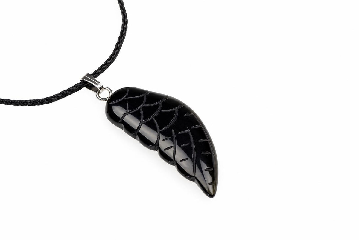 A glossy black onyx wing pendant with carved feather lines hangs from a black cord against a plain white background.